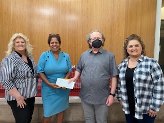 Pictured left to right: Diane White, Mercedes Veloz, Alex Tabony, and Rochell Covarruvias in front of a wooden background.